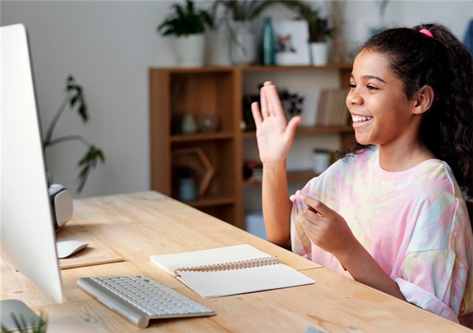 一个小学女孩在网上学习时举手提问＂height=